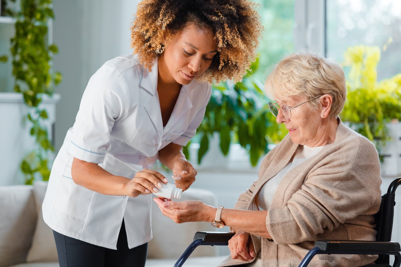 Home nurse giving medicine to senior woman